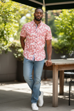 man leaning against table with floral shirt on