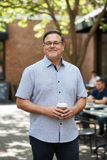 man in short sleeve shirt holding coffee cup