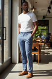 Man wearing a white t-shirt and light blue pants standing in a casual setting.