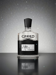 Creed Aventus perfume bottle on a reflective surface with a gray background