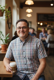Man sitting at a table in a cozy cafe holding a coffee cup