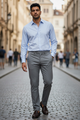 Man in light blue shirt and gray pants walking on a street.