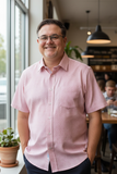 Man wearing a pink shirt standing in a casual indoor setting