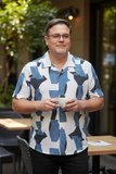 Man wearing a patterned shirt holding a cup outdoors