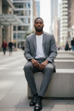 Man in a gray suit sitting on a concrete bench in an urban setting