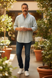 Man walking outdoors in a garden setting holding a coffee cup.