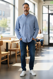 Man in a blue shirt and jeans standing in a modern cafe.