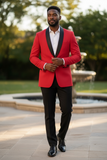 Man wearing a red blazer with black lapels and black pants standing outdoors.