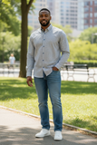 Man standing in a park wearing a checkered shirt, jeans, and white sneakers.