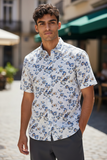Man wearing a floral short-sleeve shirt standing on a street.