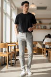 Man wearing a black t-shirt and tan pants standing in a modern cafe.
