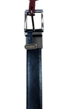 A black leather belt with a silver-toned metal buckle and a small oval brand tag reading 'REVERSIBLE', laid flat on a light wood surface.