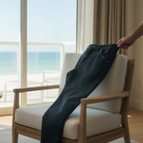 Person hanging a jacket on a chair by a large window with a view of the ocean.