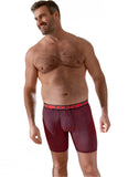 Man wearing red boxer briefs with a pattern, standing in a room with a window in the background.